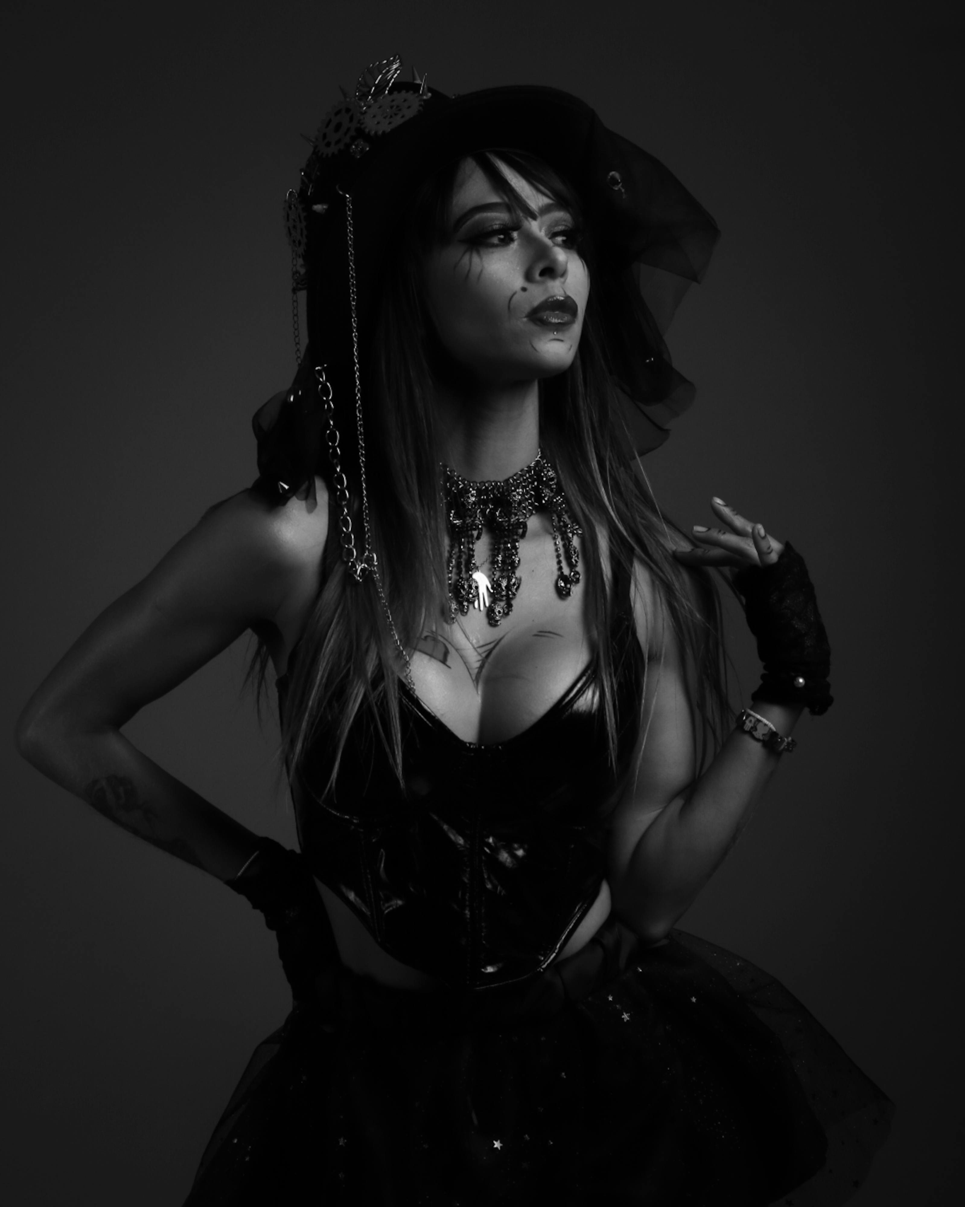 Striking black and white portrait of a gothic model wearing elegant dark attire with intricate accessories.
