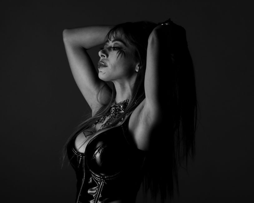 Striking black and white portrait of a woman with dramatic makeup and leather attire.