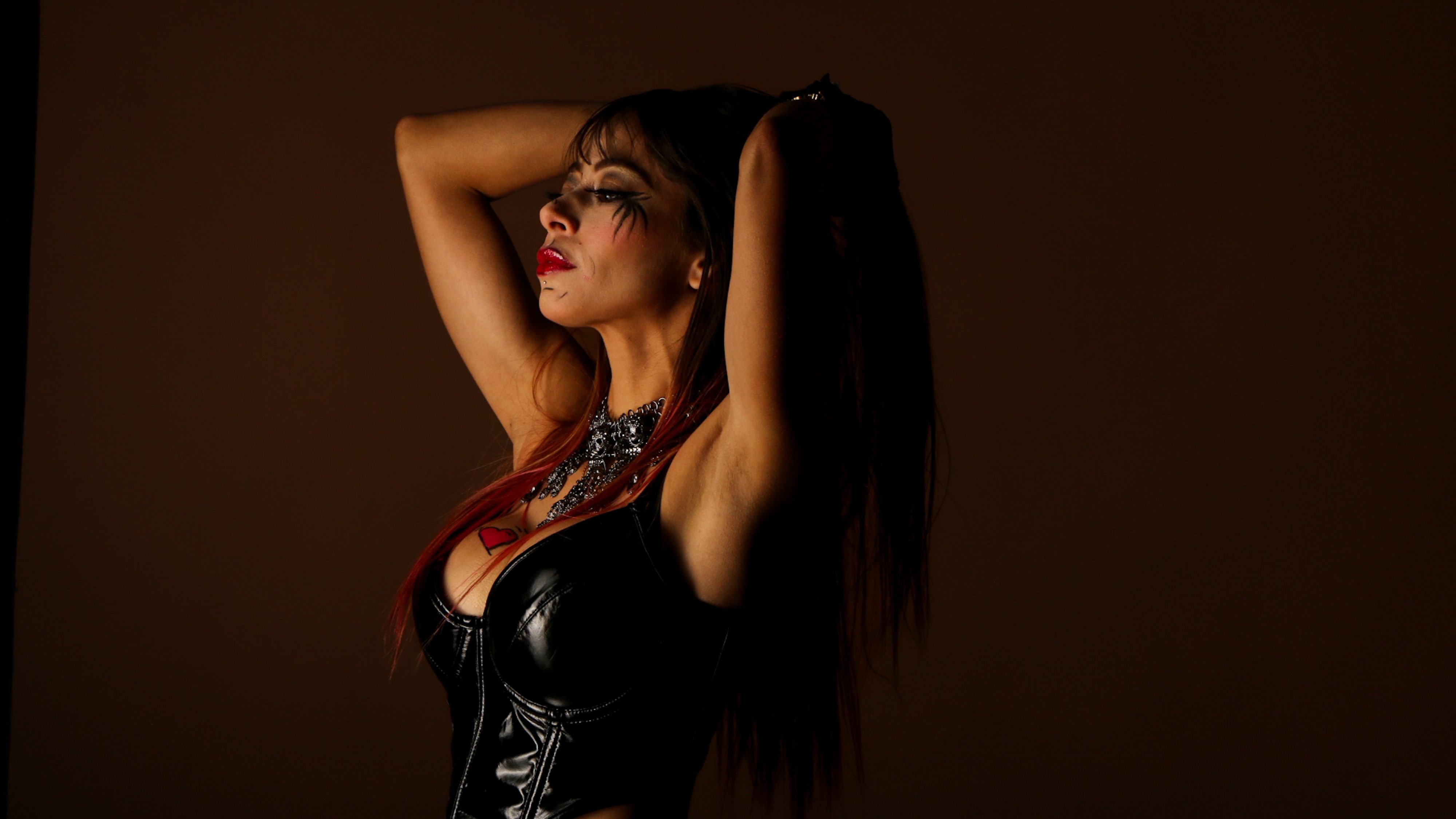 Powerful portrait of a woman in gothic attire striking a pose with dramatic lighting.