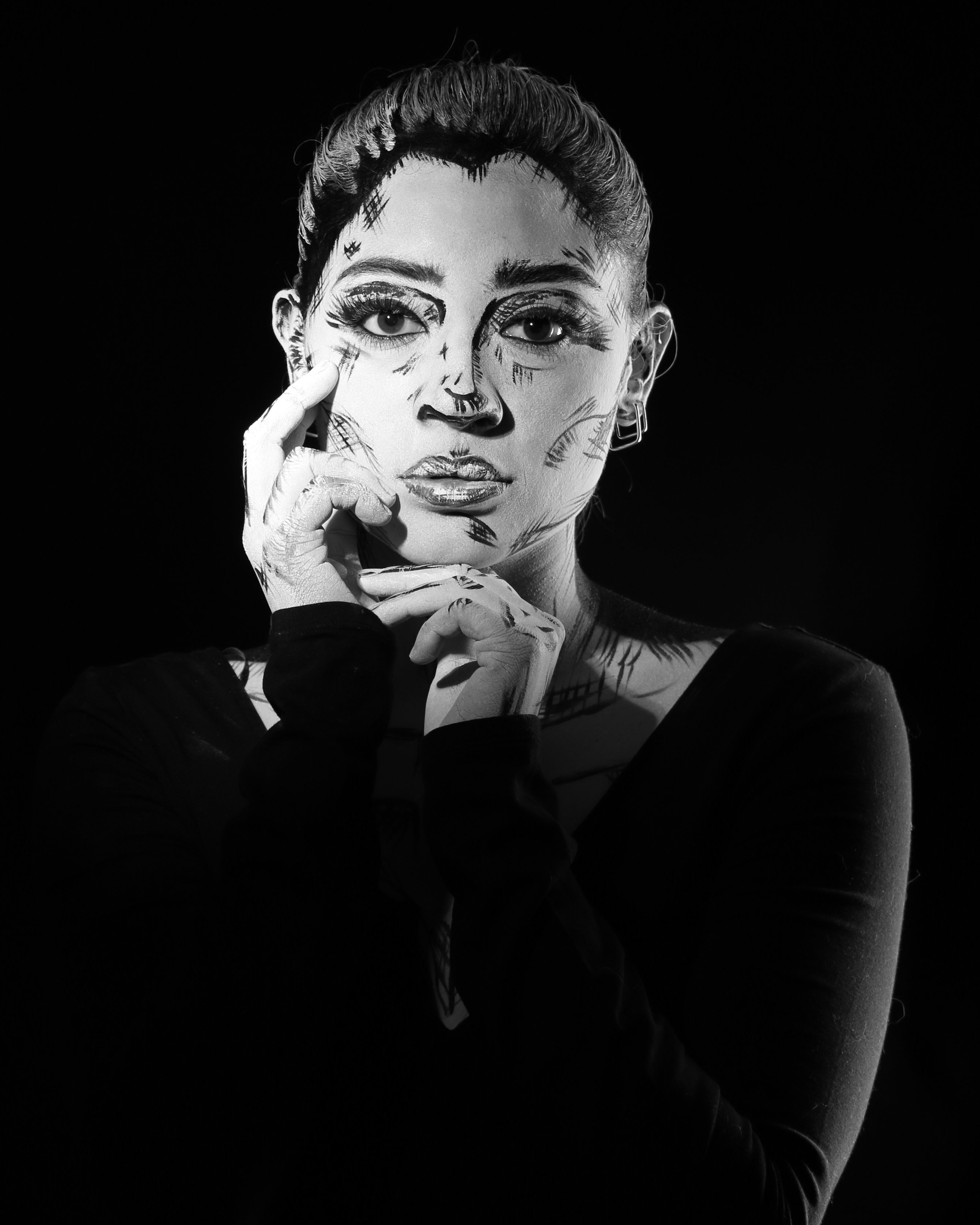 Striking black and white portrait of a woman with expressive artistic face paint.