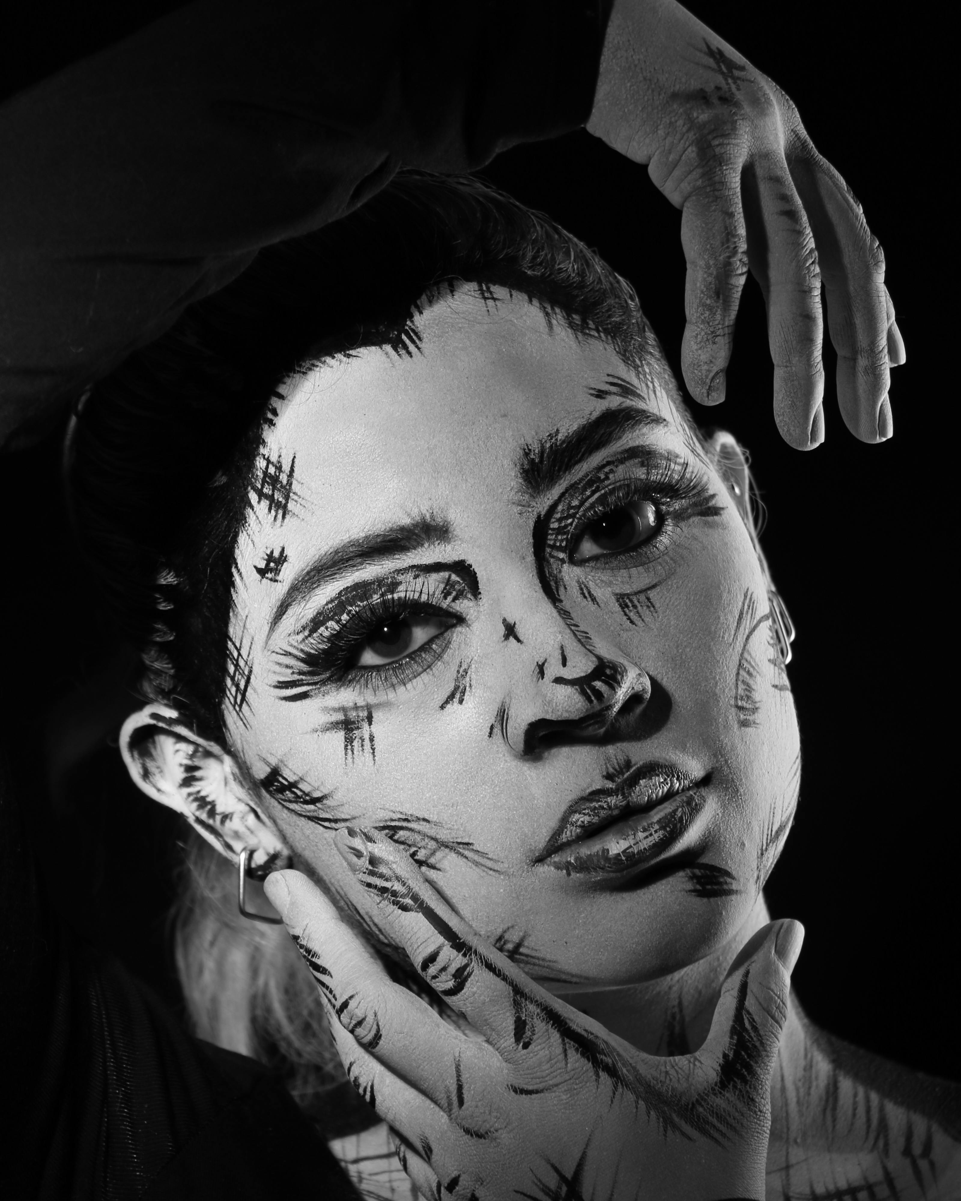 Black and white artistic portrait featuring expressive body paint on a woman's face.
