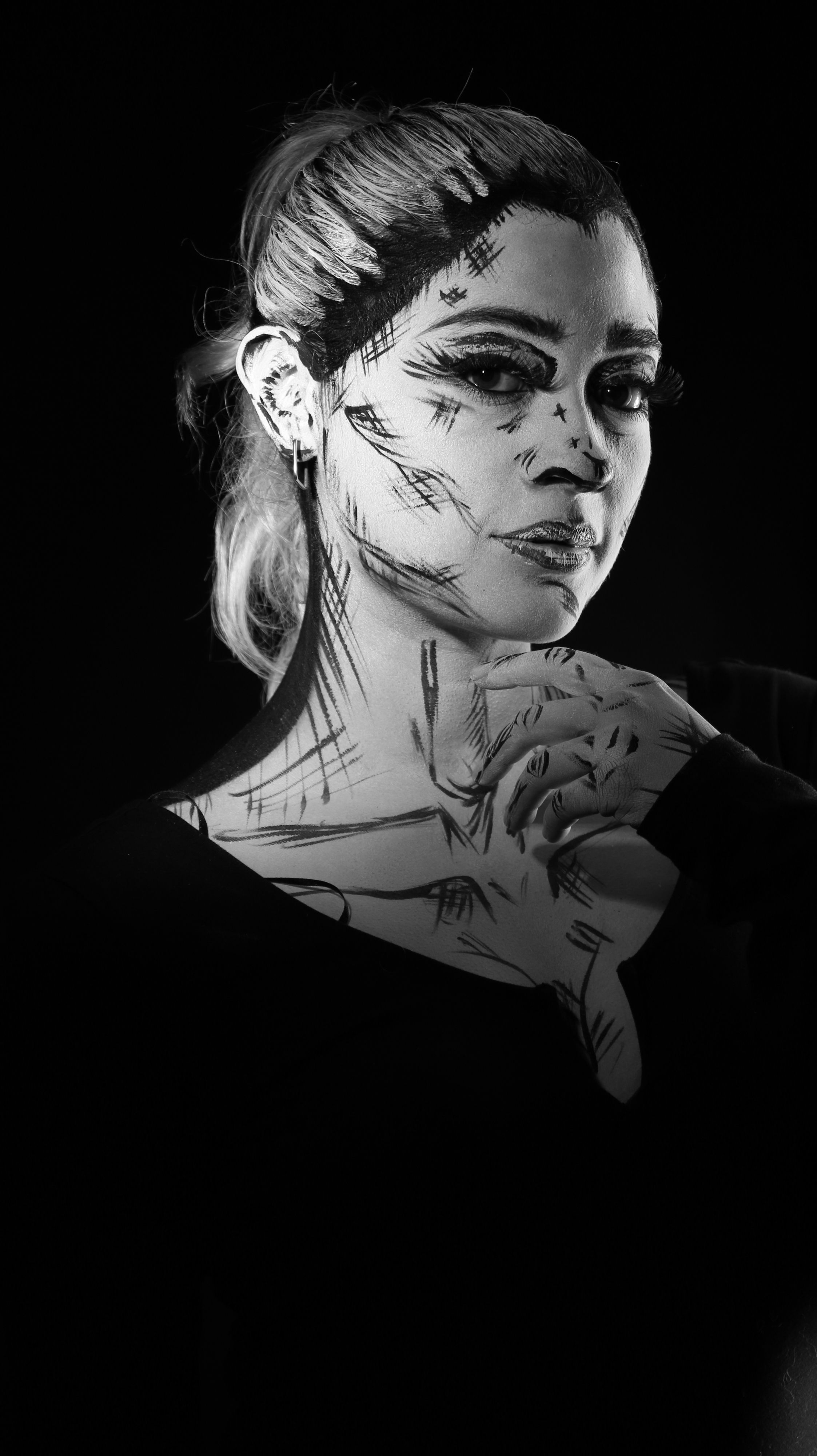 Monochromatic portrait of a woman with artistic ink strokes on skin, creating a unique visual effect.