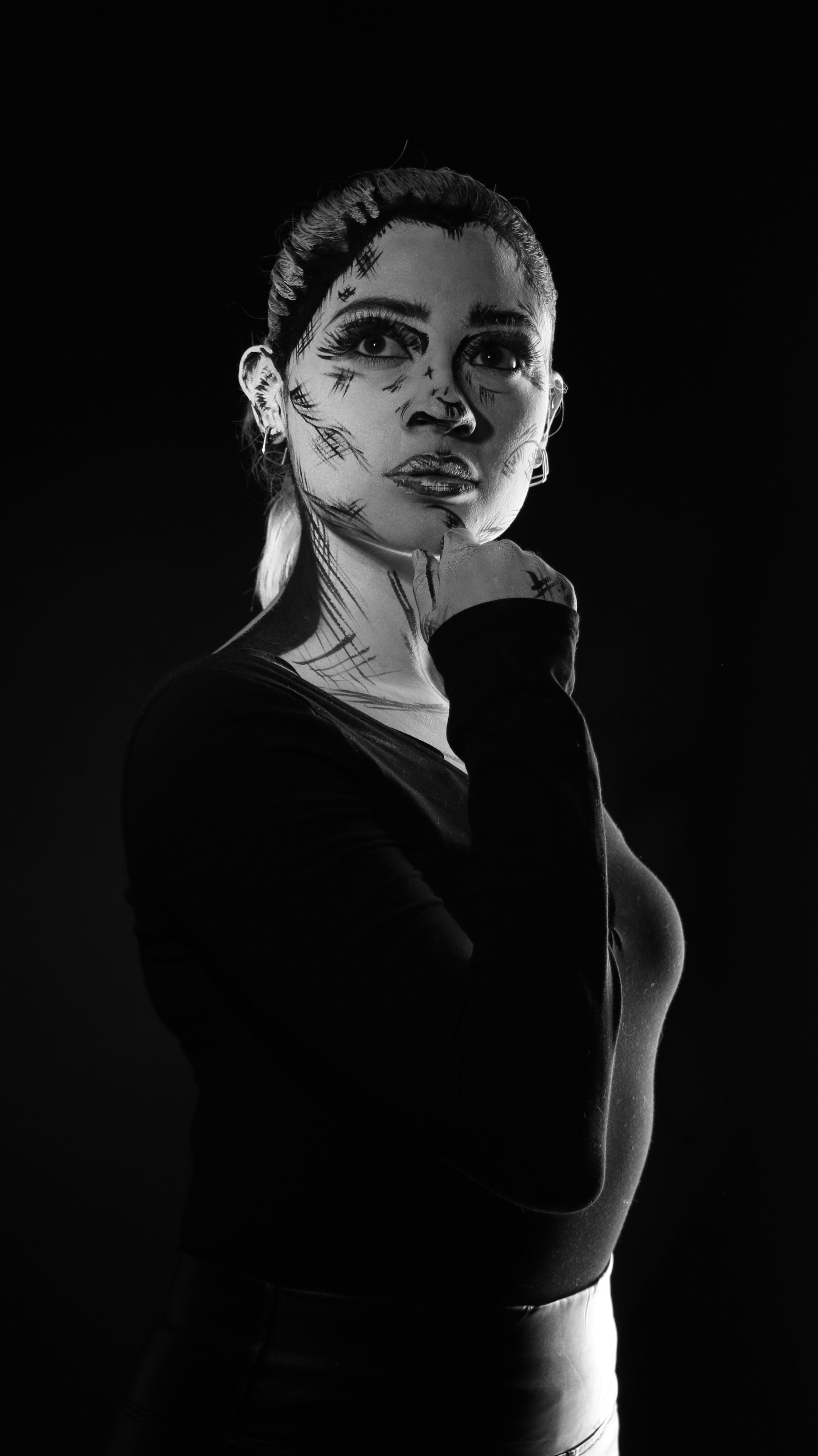 A captivating black and white portrait of a woman with artistic face paint, enhancing dramatic expression.