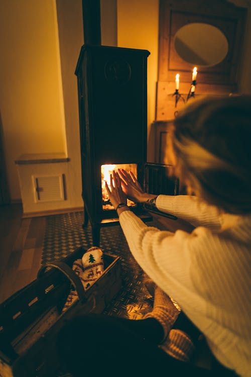 Free Woman Wearing White Long-sleeved Try to Get Heat at Fireplace Stock Photo
