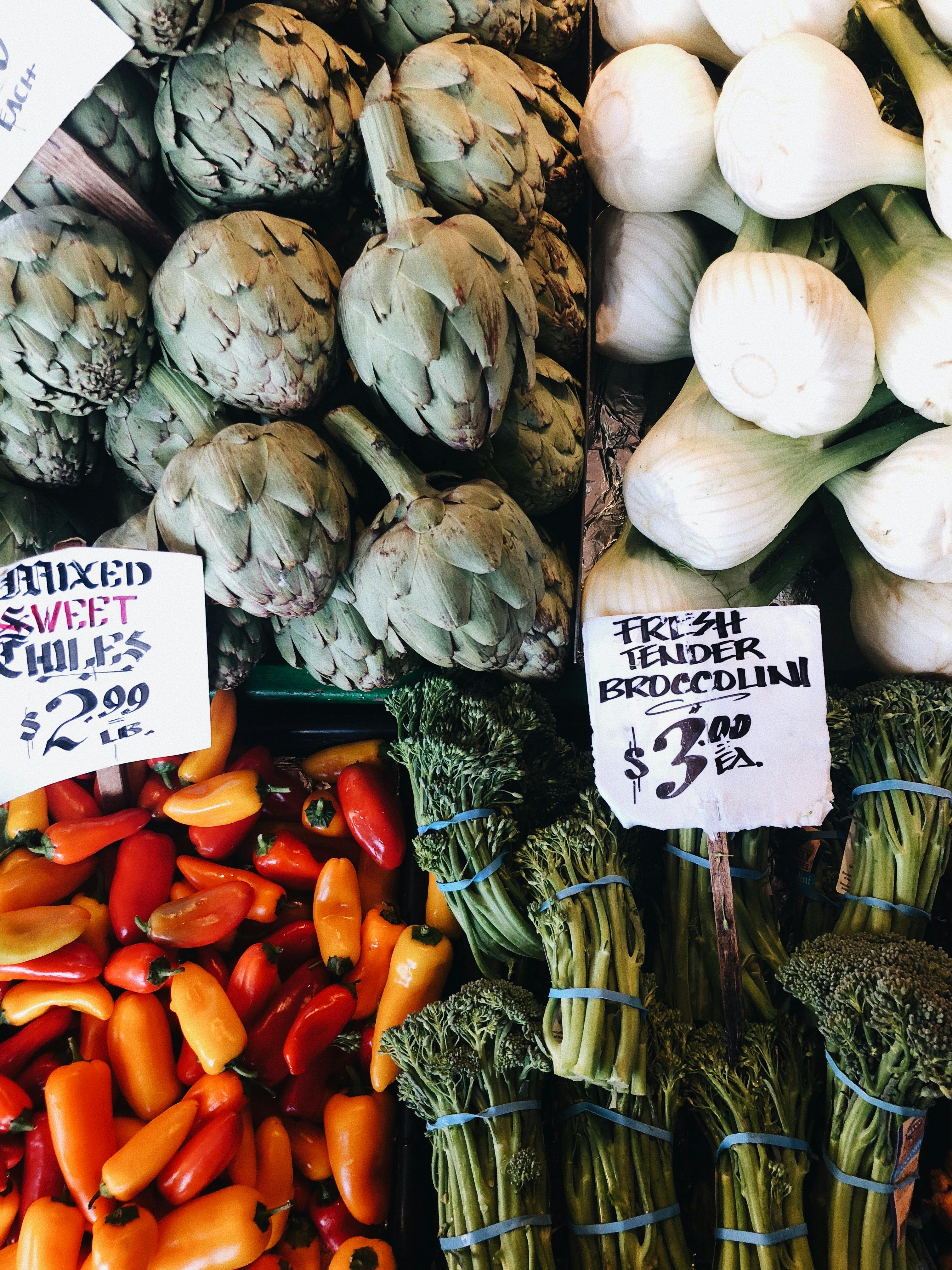 Vibrant produce selection at Seattle market featuring artichokes, peppers, and broccolini.