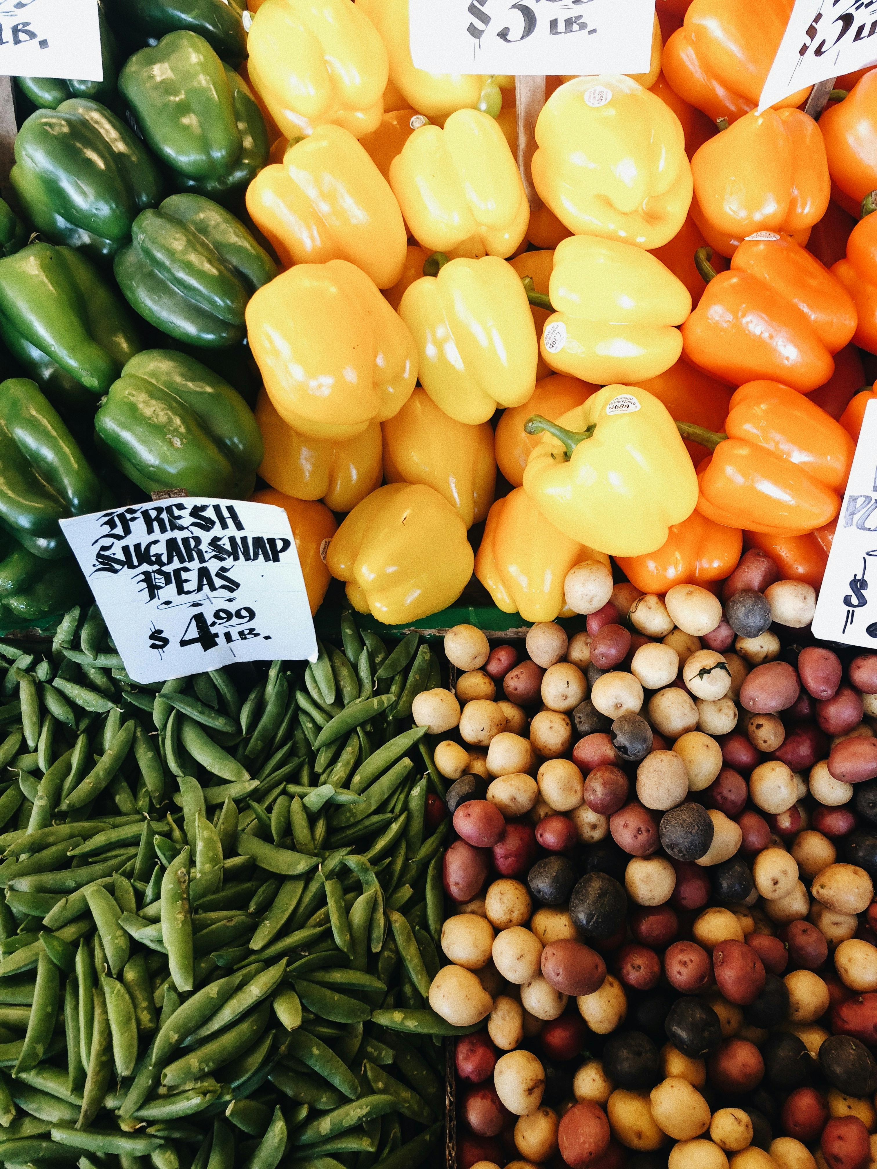 Vibrant display of bell peppers, potatoes, and sugar snap peas at a Seattle market.