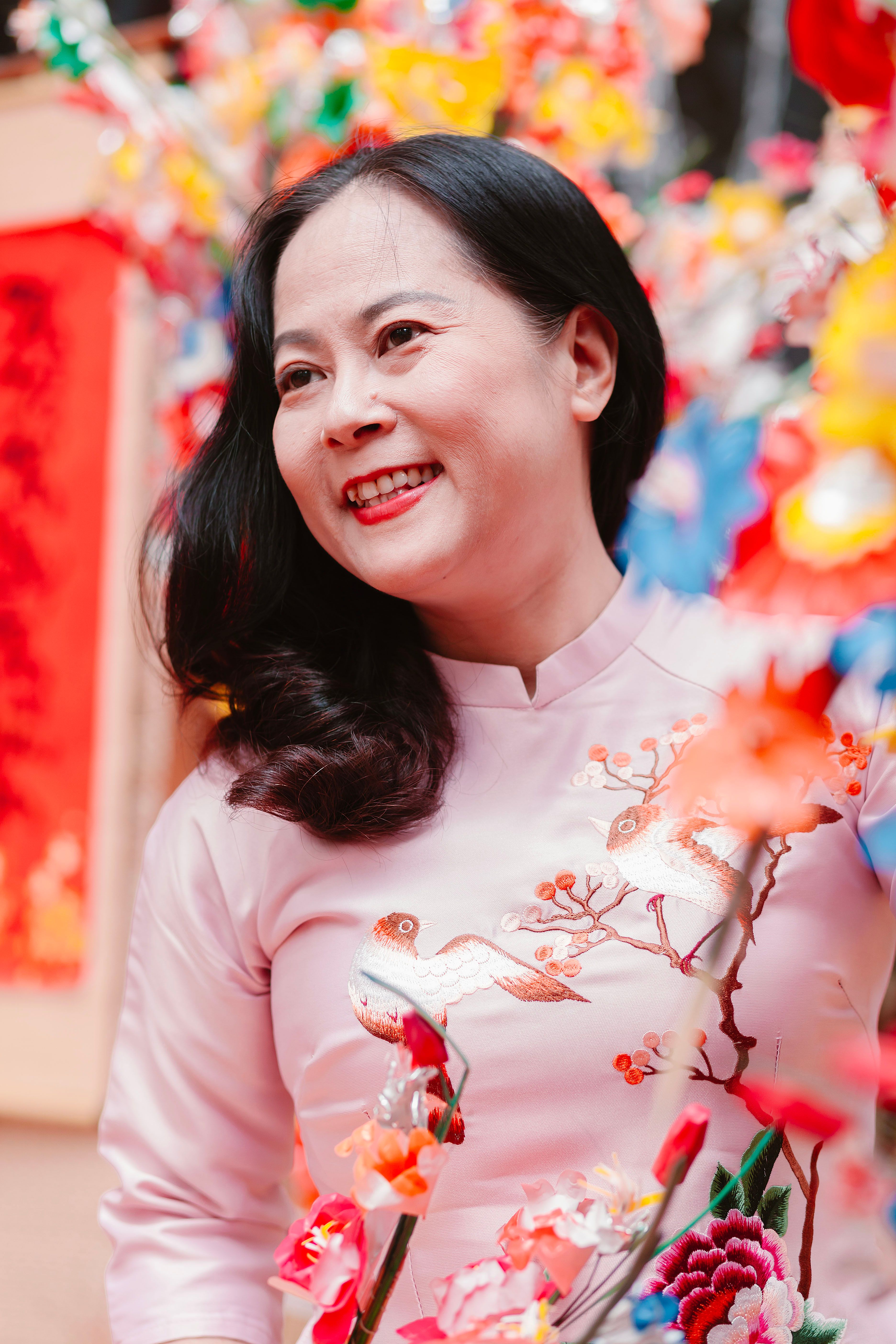 Smiling woman in floral attire enjoying festive decorations during Lunar New Year.