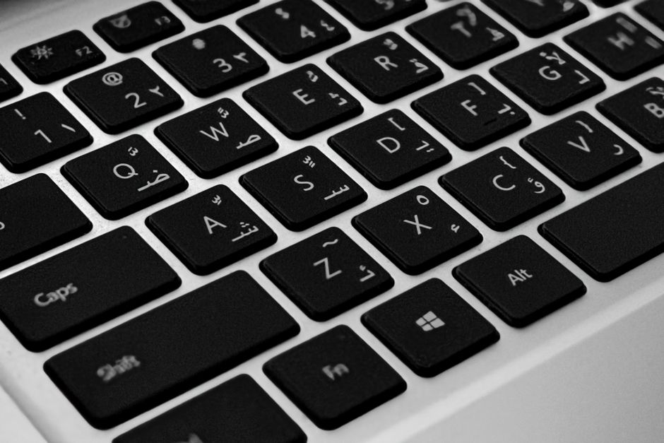 Fotomural Acercamiento en alta resolución de un teclado moderno de laptop con caracteres árabes e ingleses.