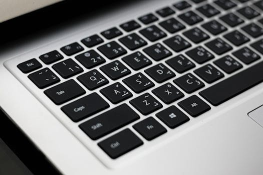 A close-up of a sleek laptop keyboard featuring both Arabic and English letters for efficient typing.