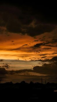 A stunning sunset with dramatic clouds casting vibrant colors across the sky over a silhouetted cityscape.