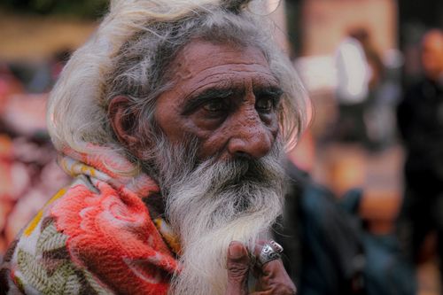 Free Close-up portrait of an elderly man with a long beard, wrapped in a vibrant blanket, on a street in India. Stock Photo