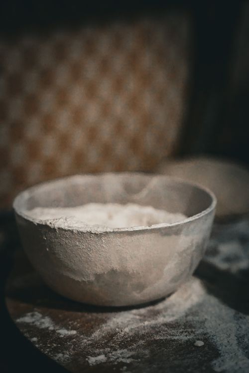 Free A rustic bowl filled with flour placed on a wooden table, creating a vintage baking atmosphere. Stock Photo