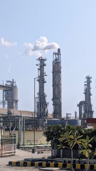 A detailed view of a chemical plant's tall chimneys and industrial structures against a clear sky.
