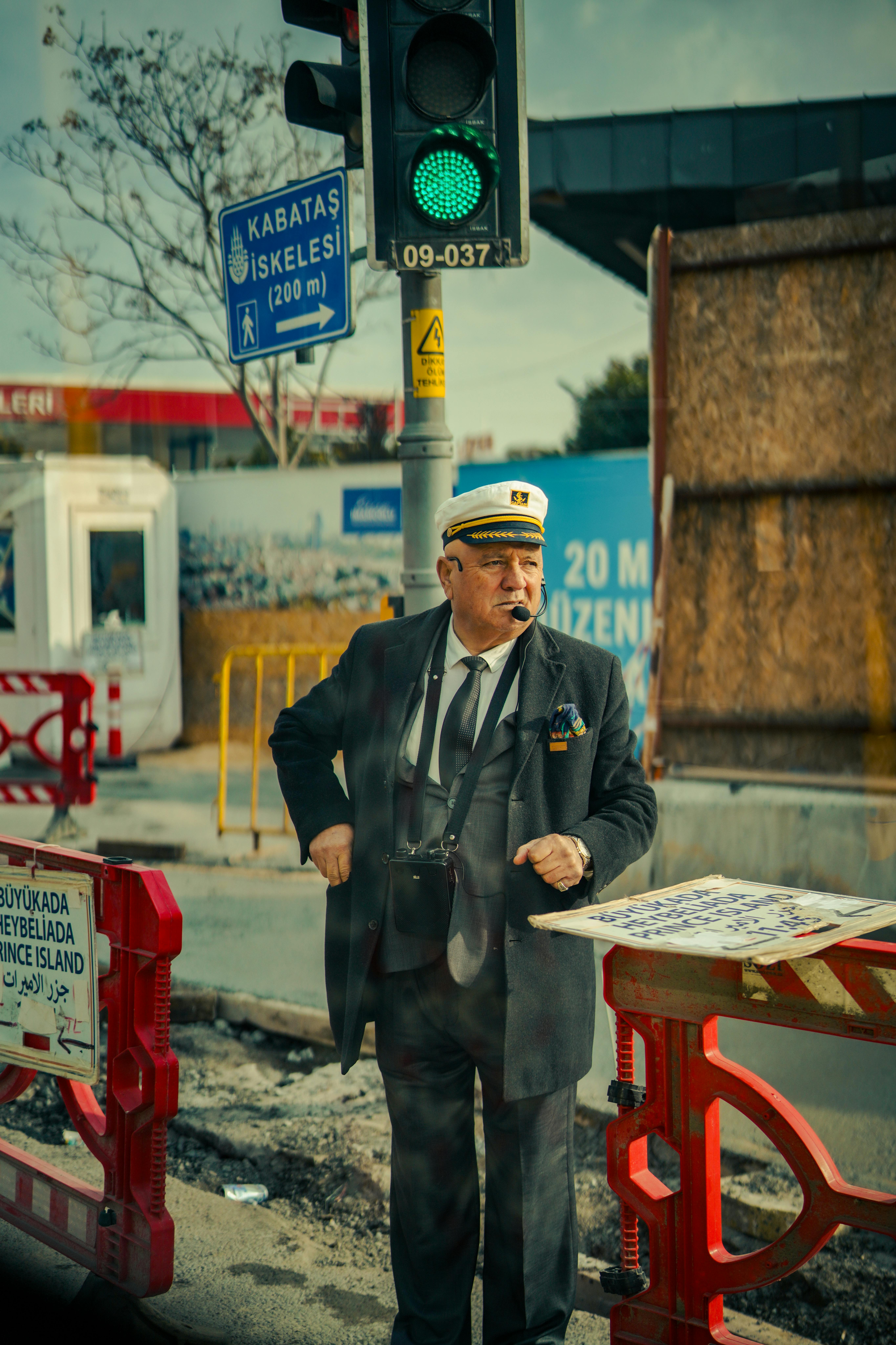 An elderly man in uniform directing traffic near a ferry terminal in Istanbul.