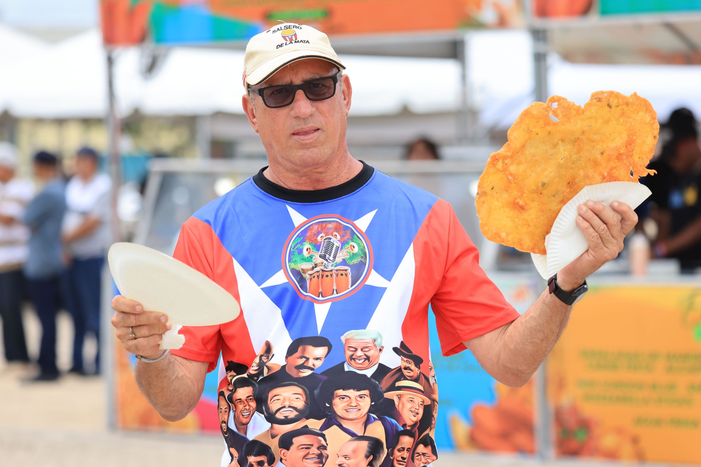 A man savoring a tostada at an outdoor food stand in Puerto Rico, plate in hand