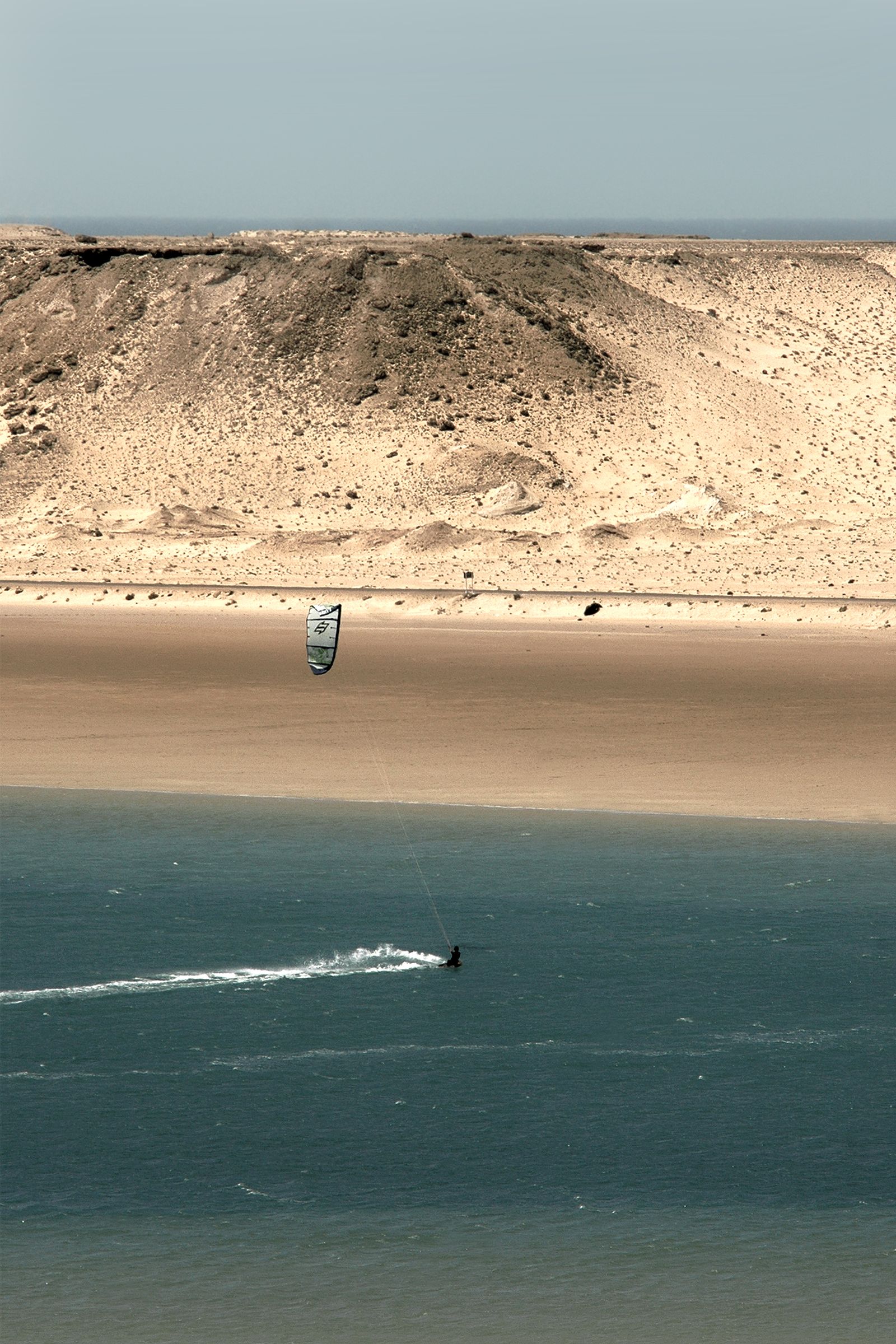 Kitesurfing against desert cliffs — Dakhla, Morocco