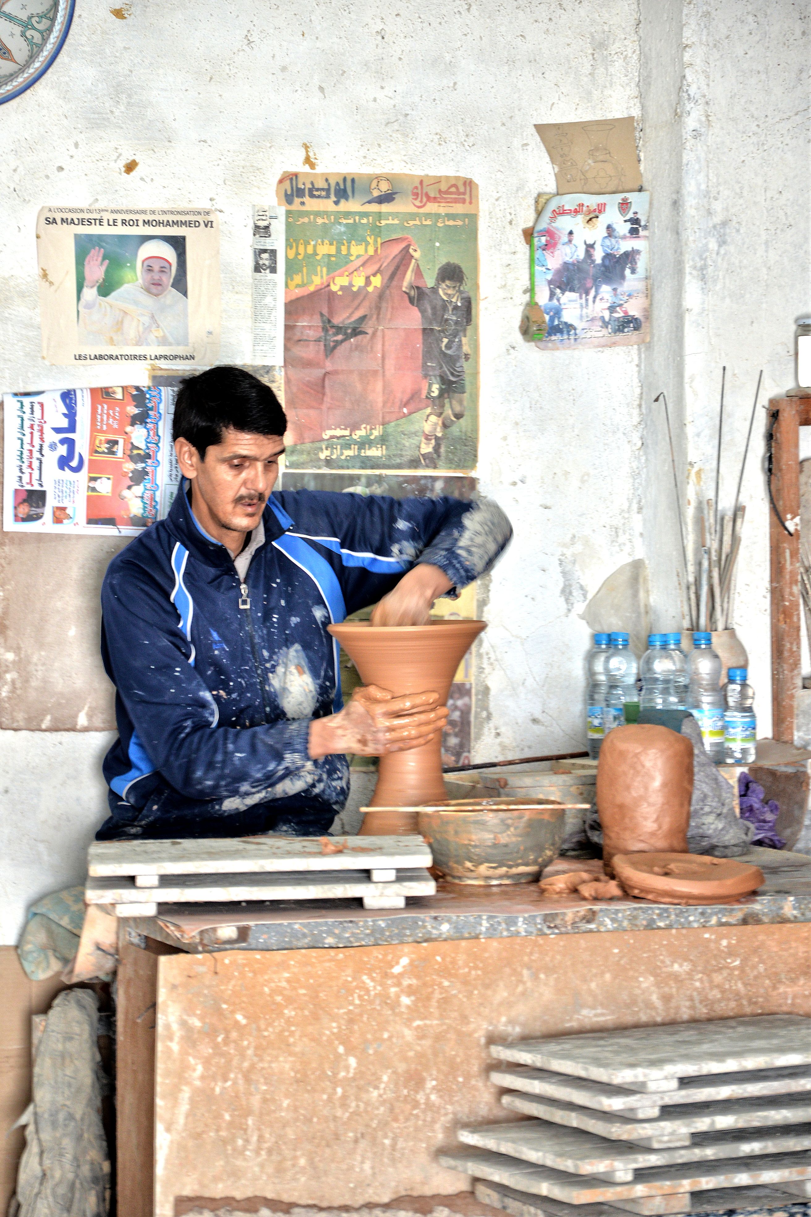 A skilled artisan crafts a clay pot in a traditional Fès workshop, showcasing Moroccan pottery techniques.