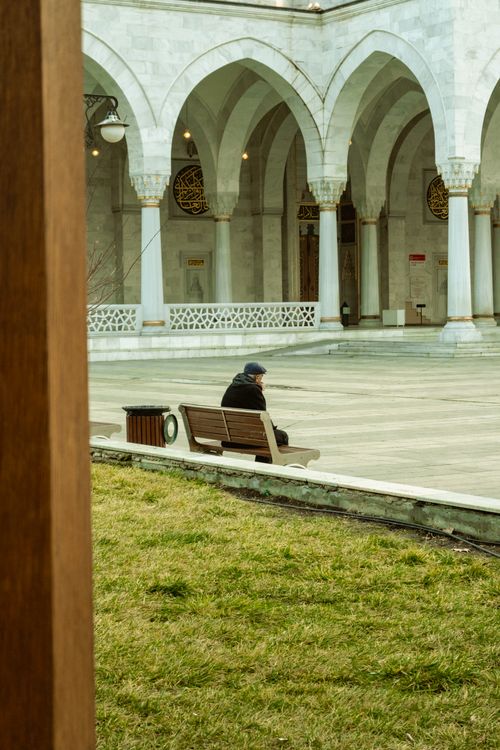 Free Elderly man sitting alone on bench in historic Ankara courtyard, reflecting tranquility. Stock Photo