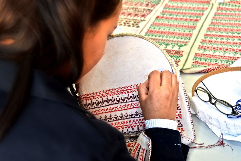 Artisan brodant un logo au fil sur un vêtement professionnel dans un atelier