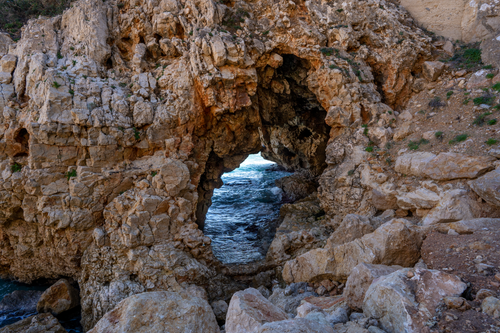 Free Majestic view through a rocky arch revealing the vibrant Mediterranean Sea in Benitachell, Spain. Stock Photo
