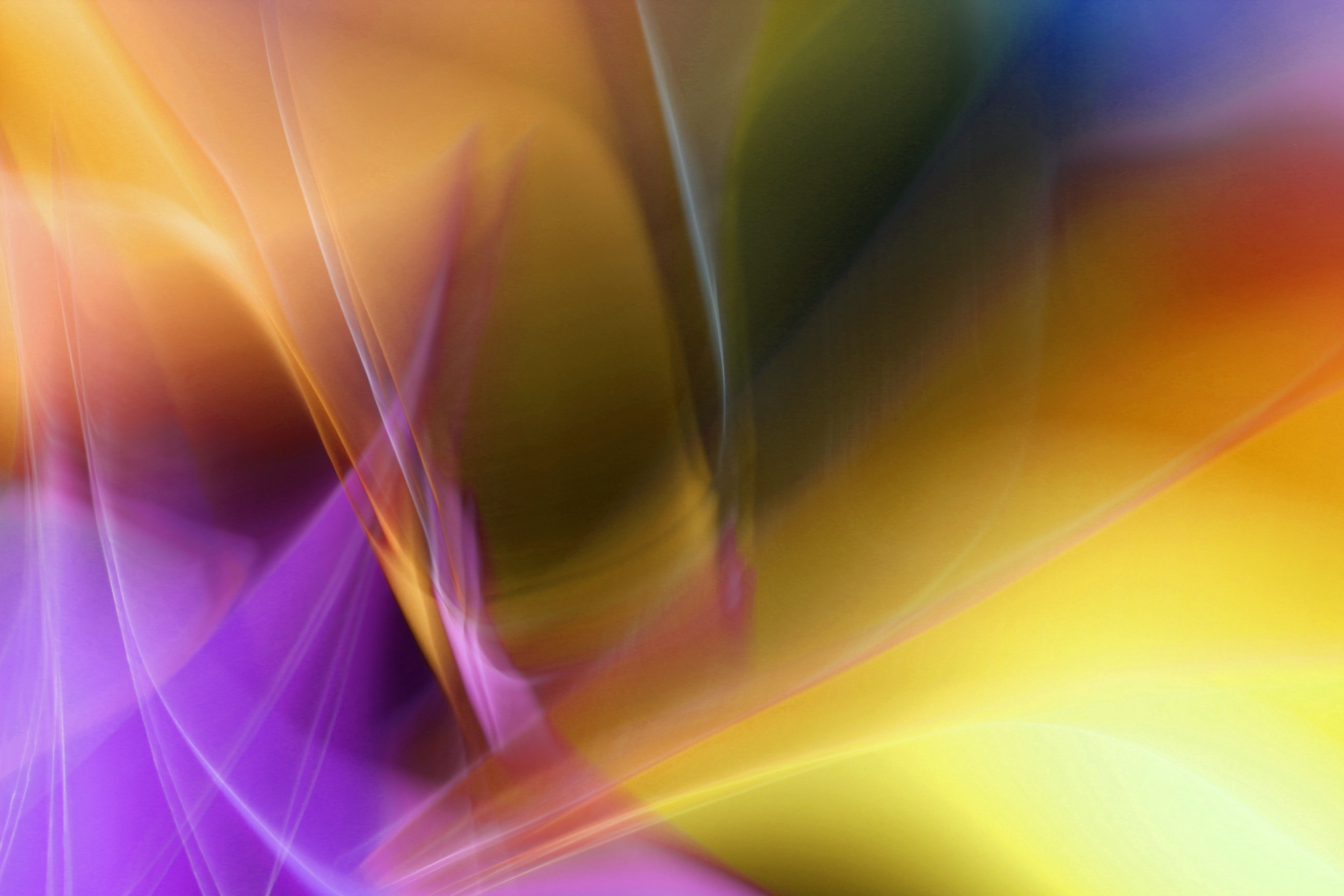 Colorful abstract art with swirling light patterns, featuring a blend of purple, yellow, and orange hues.