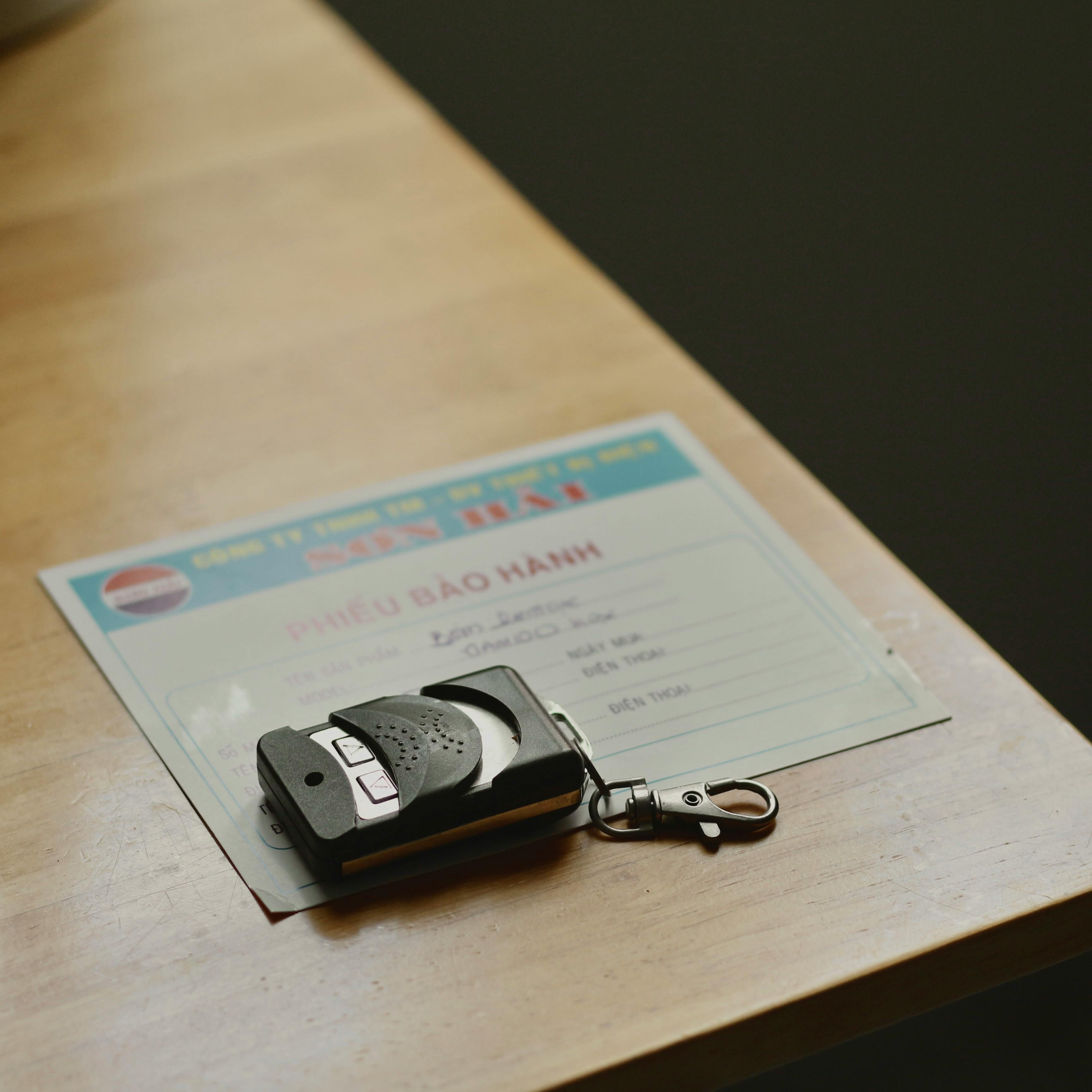 Free Remote control device resting on a warranty document placed on a wooden table. Stock Photo