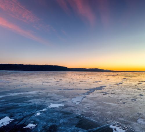 Free Serene view of Lake Pepin's frozen expanse with a vibrant sunrise sky in winter. Stock Photo