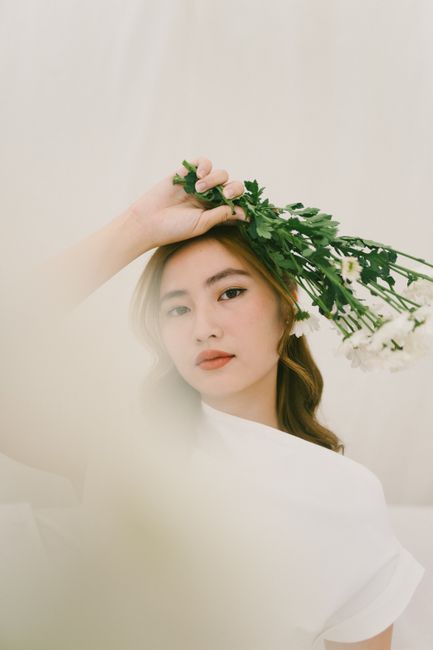 A stylish woman poses with flowers, exuding grace and elegance.