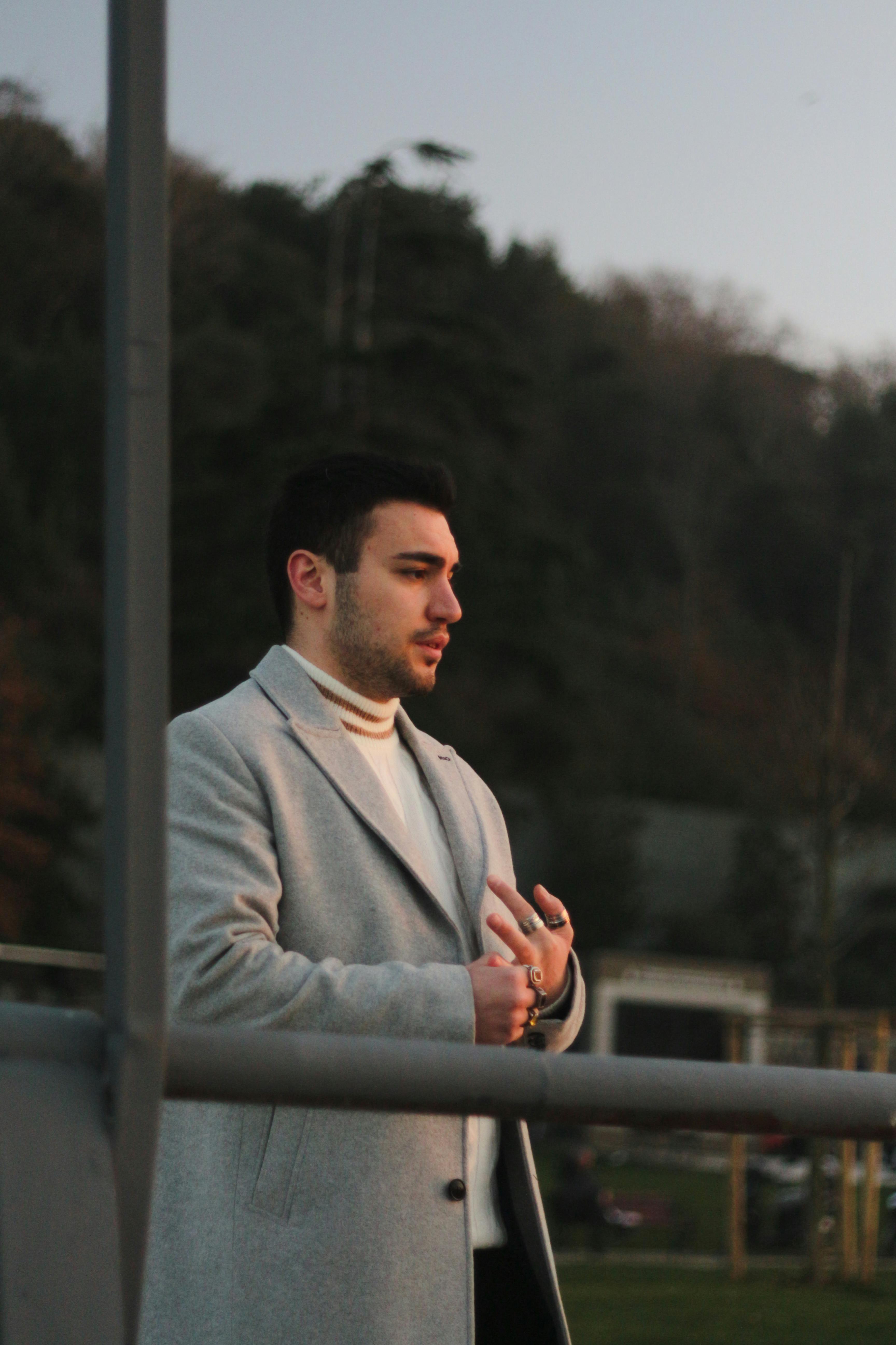A man in a gray coat enjoying the scenic sunset in Istanbul, T&uuml;rkiye.
