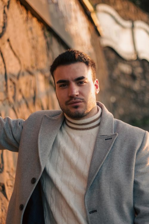 Free A young man elegantly posing against an outdoor wall in Kuzguncuk, İstanbul, Türkiye. Stock Photo