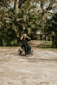 Elderly woman in wheelchair enjoying a tropical park, surrounded by lush greenery.