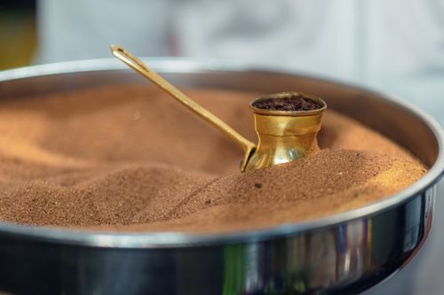 Free Close-up of Turkish coffee brewing in a cezve placed in heated sand at a cafe. Stock Photo
