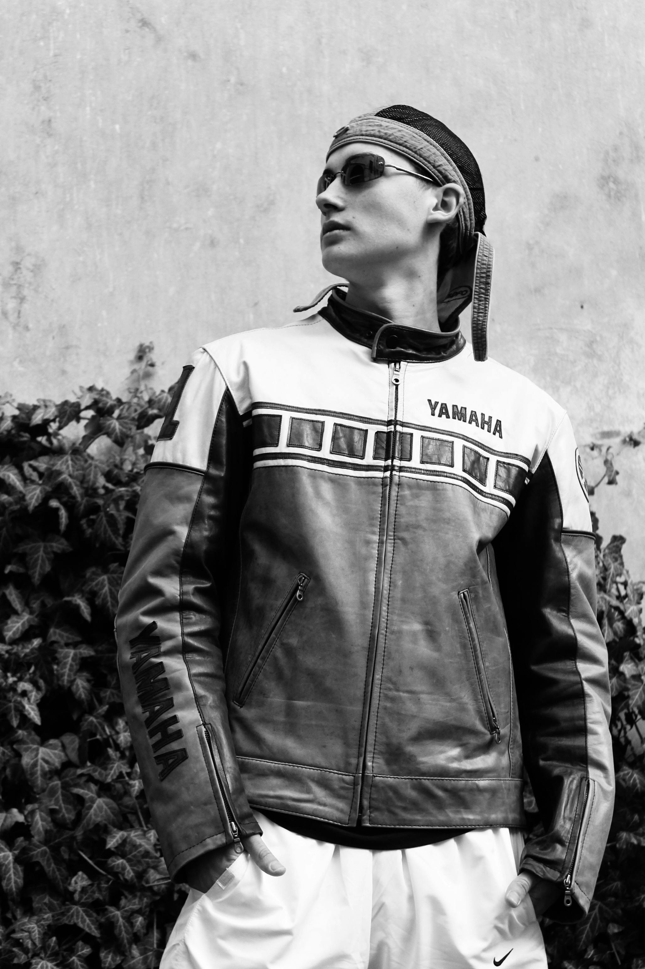 Black and white portrait of a biker in a Yamaha leather jacket outdoors.