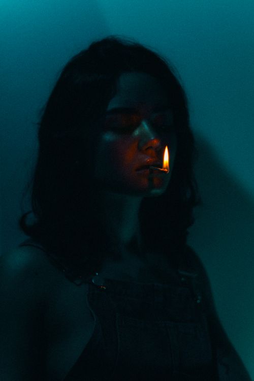 Free Artistic portrait of woman in dark moody lighting holding a flame with an ethereal atmosphere. Stock Photo
