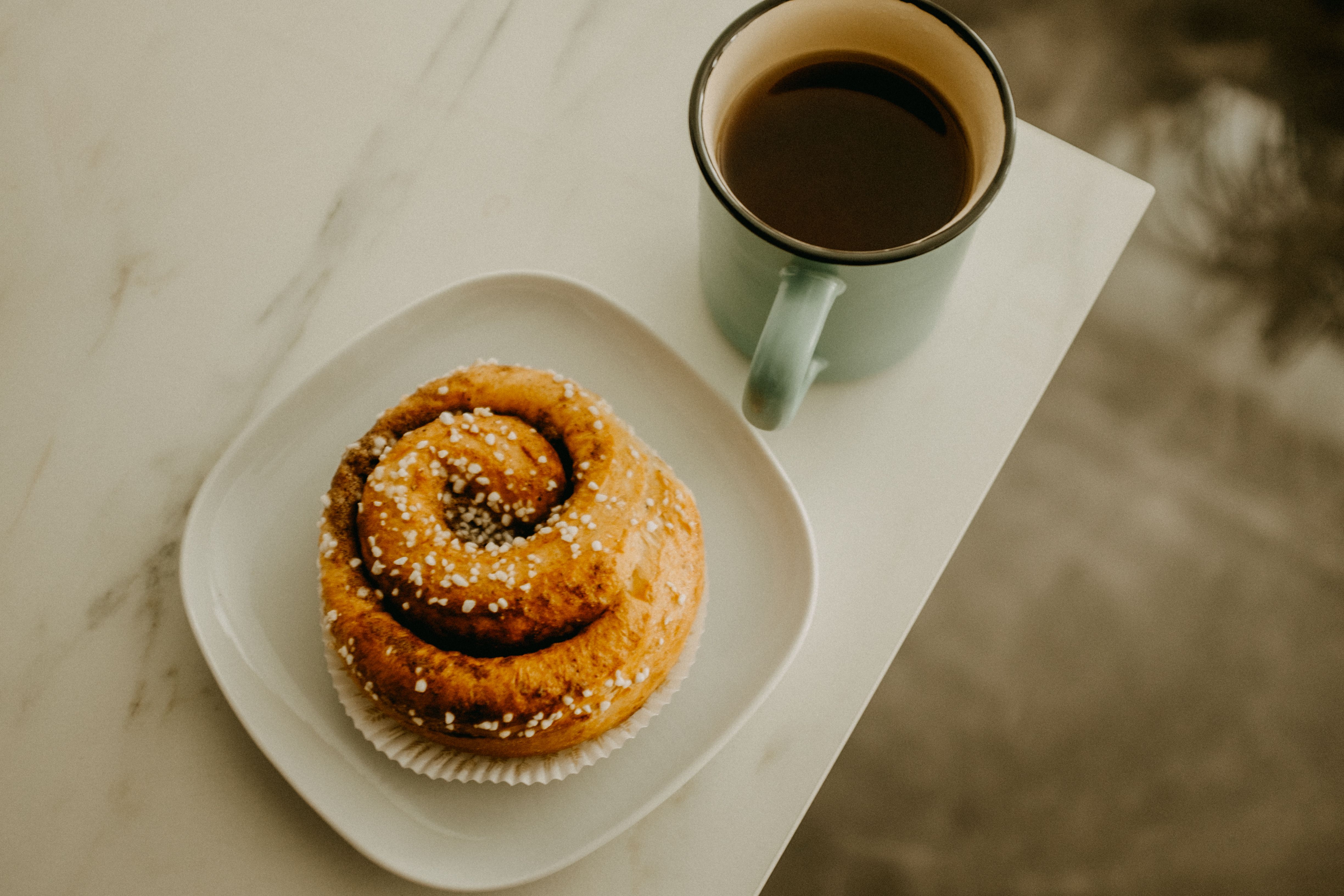 Tasse Kaffee neben einem kleinen Teller mit Gebäck
