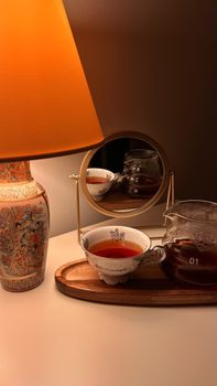 Warm ambient setting featuring a teapot, cup, and vintage lamp.
