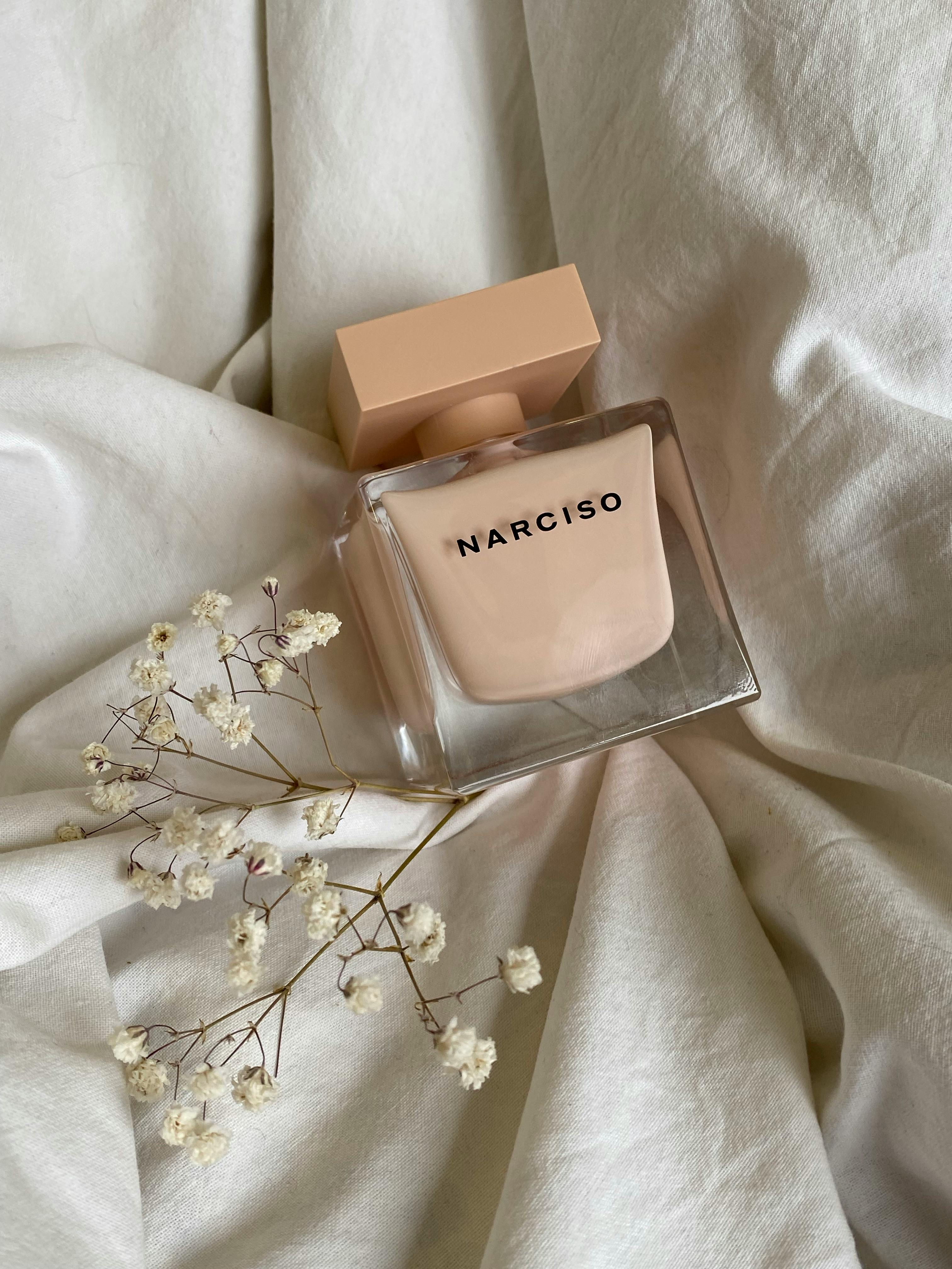 A chic Narciso perfume bottle on delicate fabric with dried flowers, enhancing elegance.