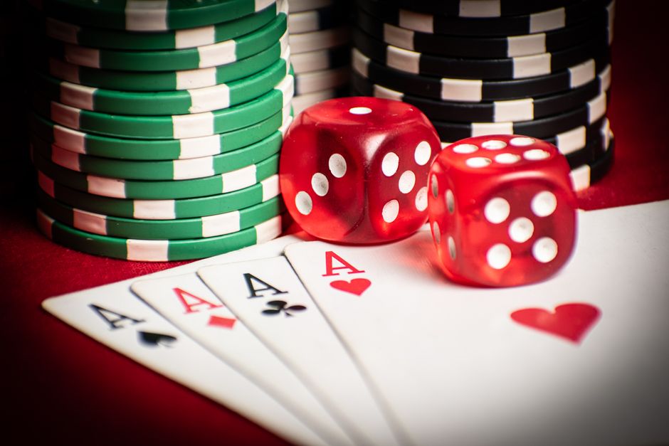 Close-up of poker hand with dice and chips, symbolizing casino gaming.