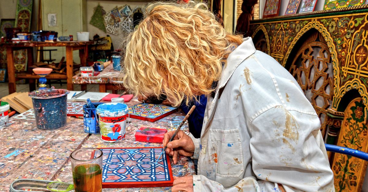 Artist focuses on creating a vibrant traditional Moroccan pattern in Fès workshop.