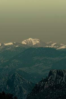 Stunning view of snow-capped mountain peaks under a serene green sky, creating a tranquil landscape.