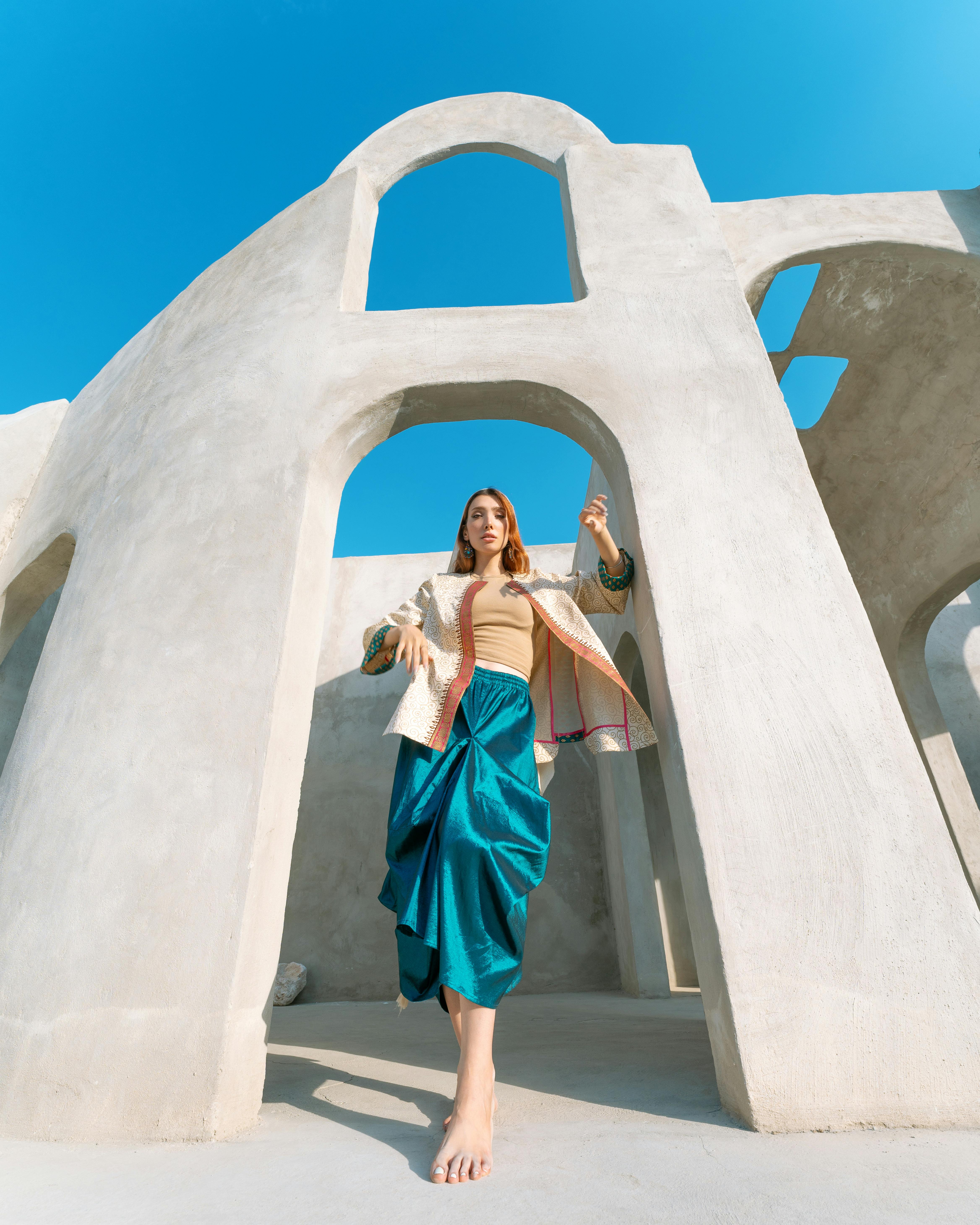 Artistic photo of a woman in colorful attire amidst modern concrete arches.