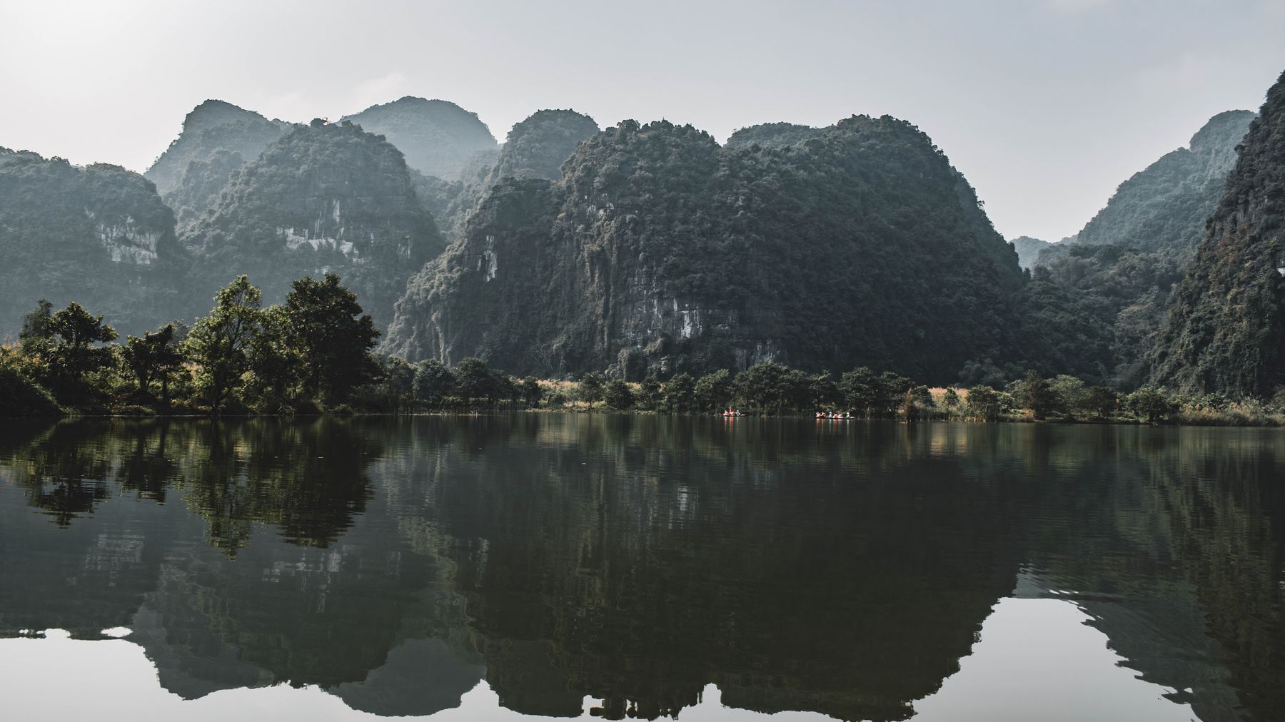 Phản chiếu yên bình của những ngọn núi đá vôi trên mặt nước tĩnh lặng tại Ninh Bình, Việt Nam.