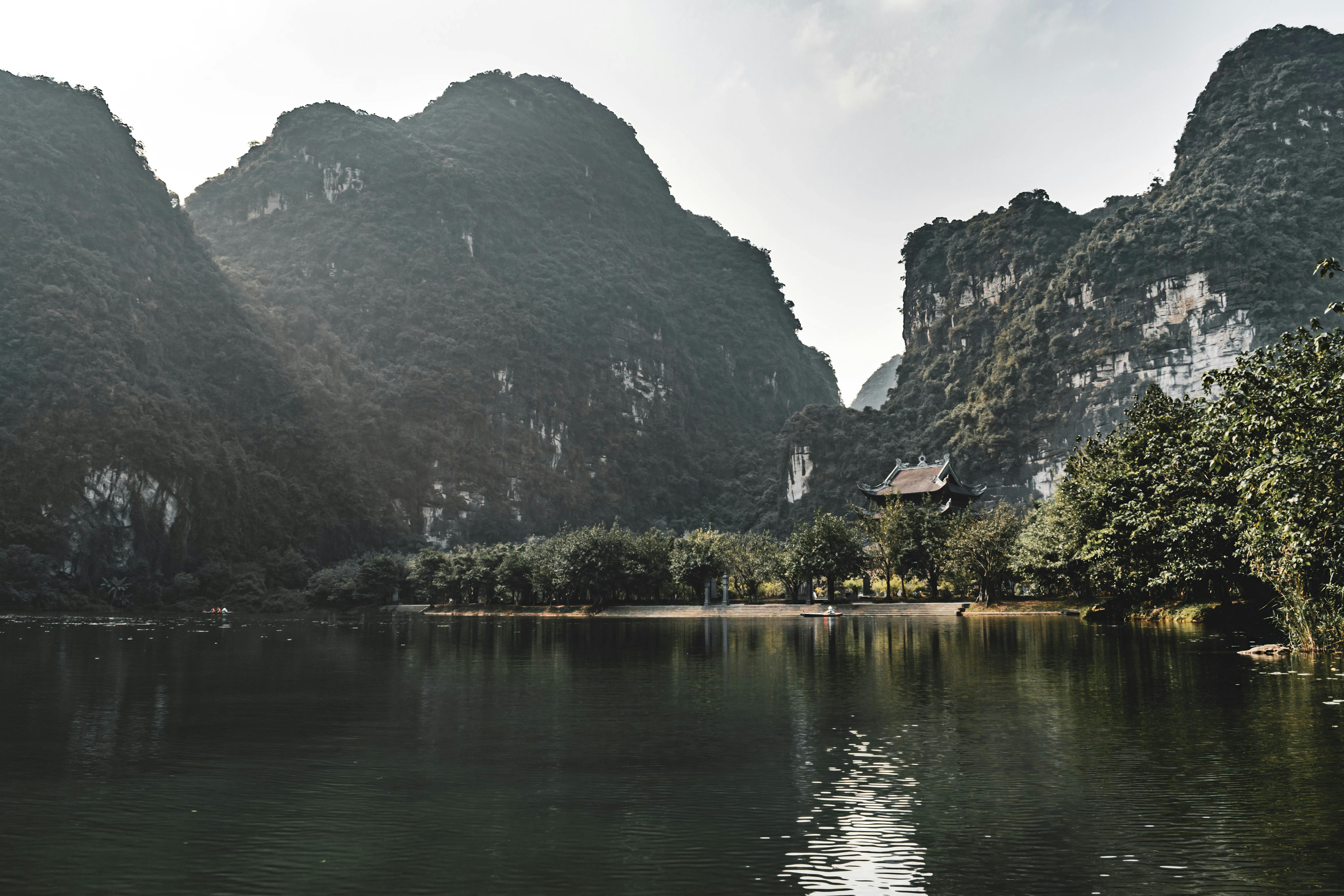 Peaceful waters reflecting dramatic limestone mountains in Hoa Lư, Ninh Bình, Vietnam.