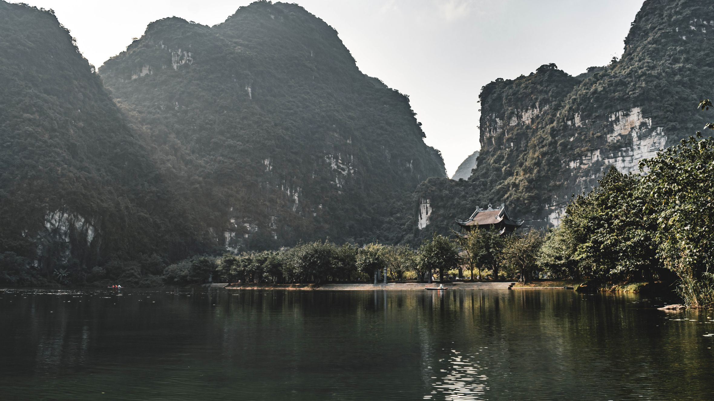 Peaceful waters reflecting dramatic limestone mountains in Hoa Lư, Ninh Bình, Vietnam.