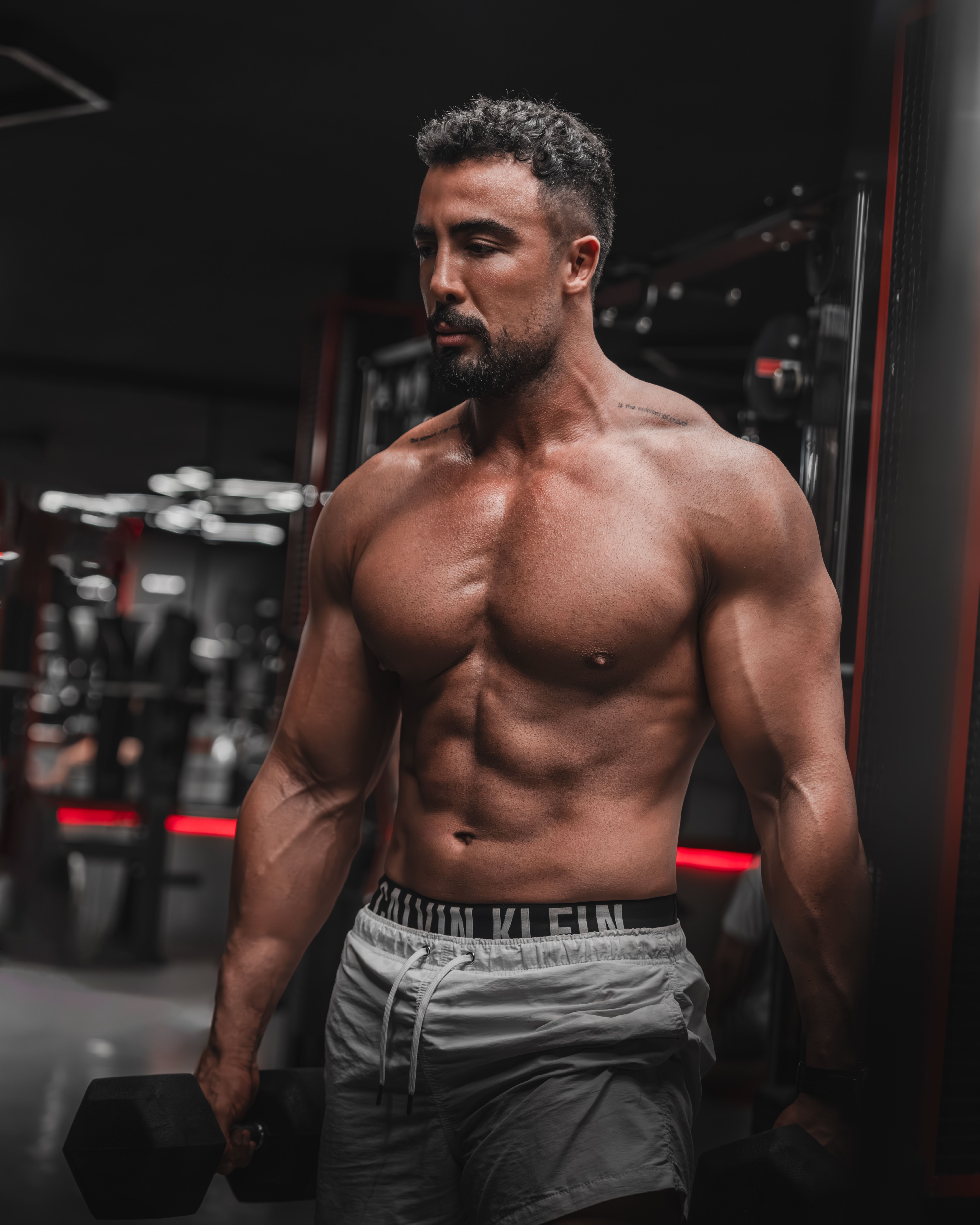 Strongly built man lifting weights in a modern gym.