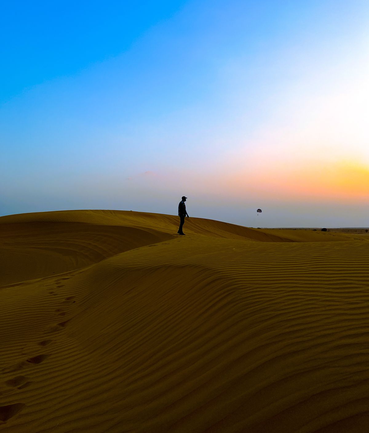 Lone figure standing on a dune crest at sunset in the Thar Desert