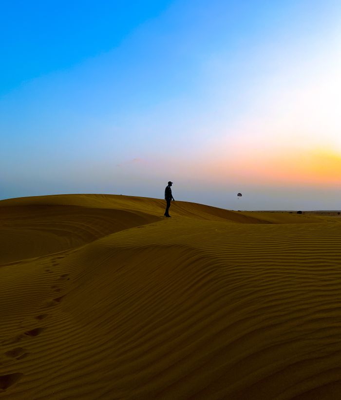 Lone figure standing on a dune crest at sunset in the Thar Desert