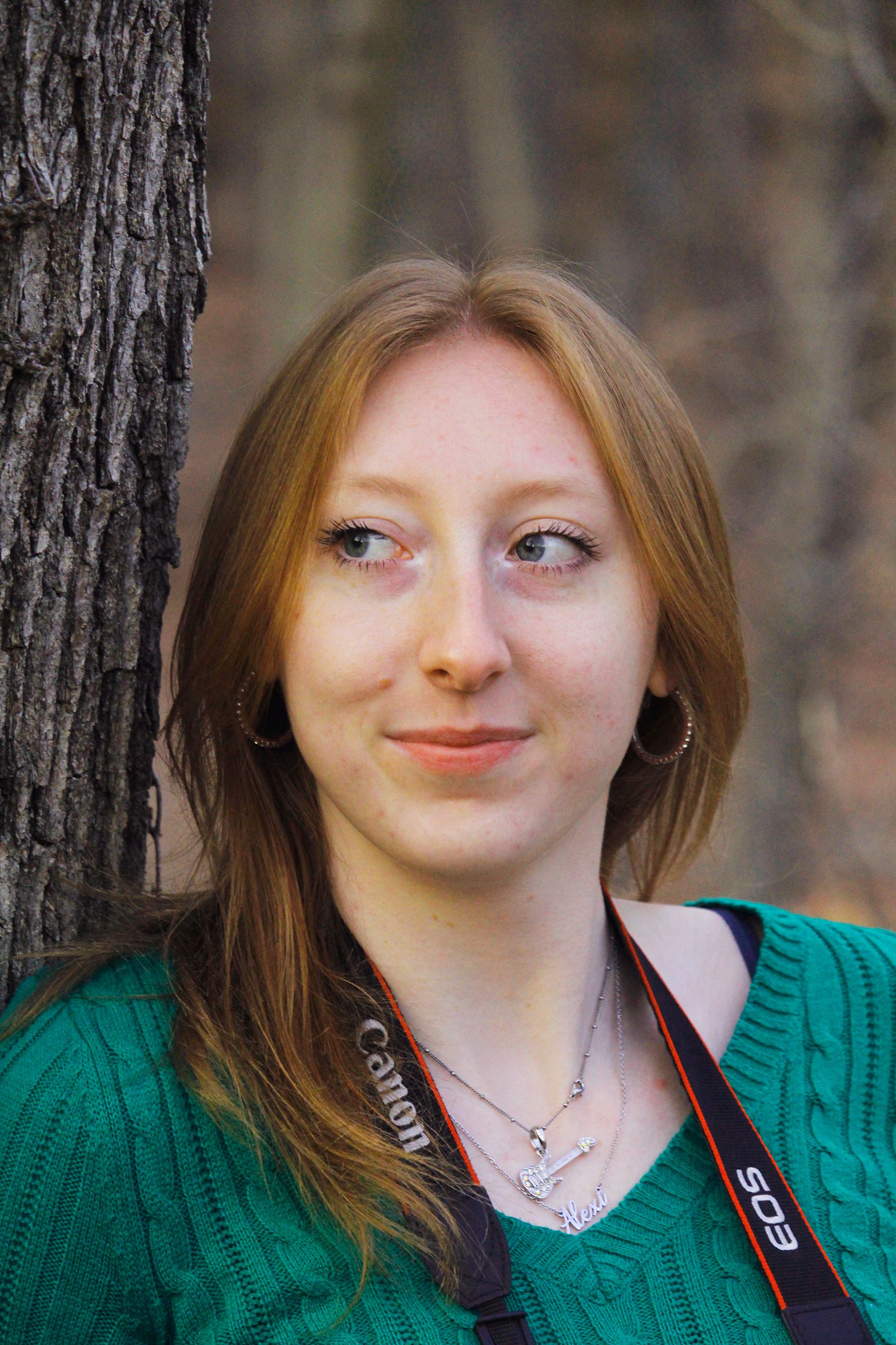 Portrait of a young woman outdoors with a camera, capturing the fall season.