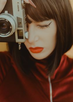 Editorial fashion portrait featuring a model in red with a vintage camera, embodying stylish retro vibes.