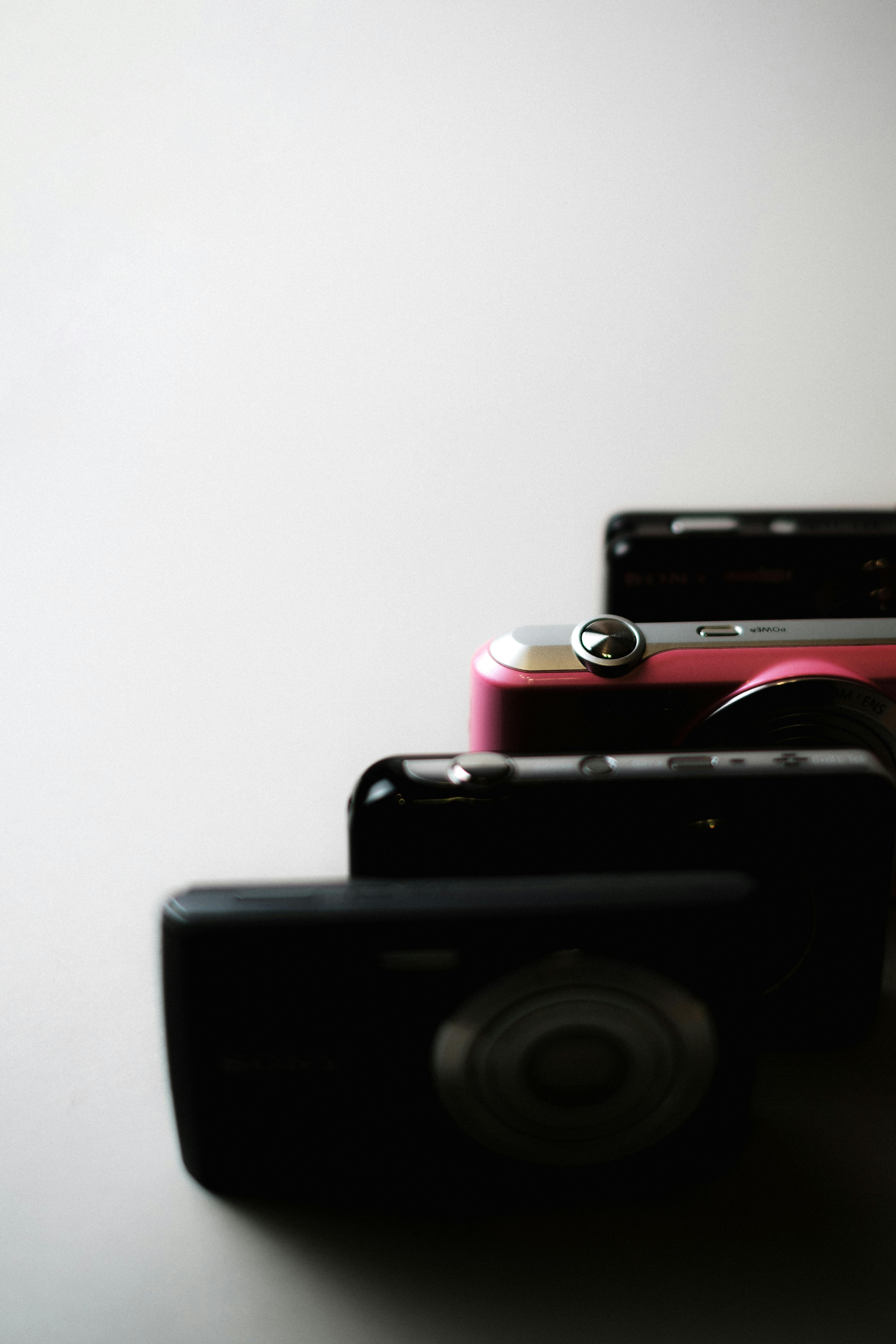 무료 미니멀한 디자인과 세련된 색상 대비가 특징인 빈티지 컴팩트 디지털 카메라 3대가 정렬되어 있습니다. 스톡 사진